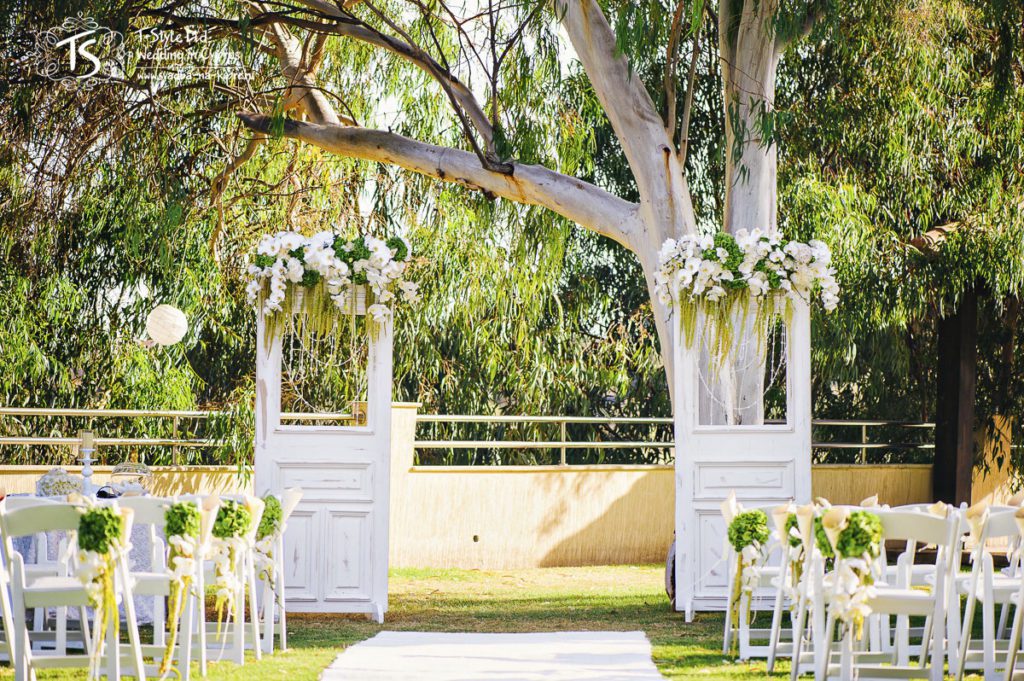 Место церемонии, декорированное аркой в виде дверей, деревянными стульями, белой ковровой дорожкой