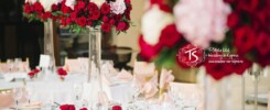 Прозрачные вазы на высокой ножке с композициями из красных пионовидных роз и гортензии розового цвета с небольшим добавлением зелени